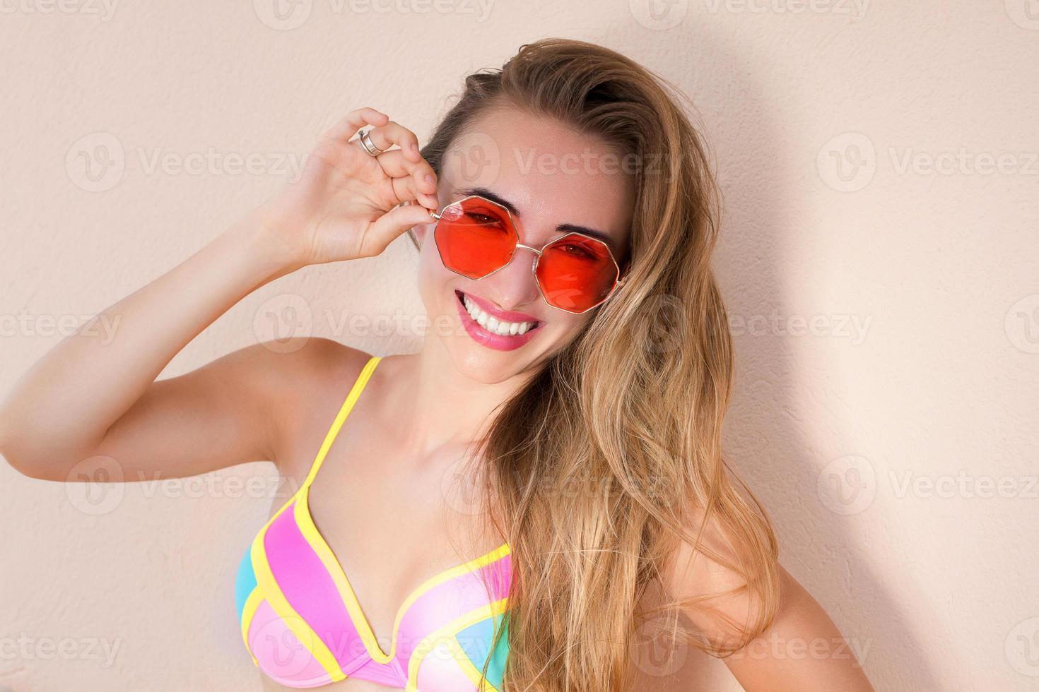 Close Up Of Happy Girl in pink sunglasses isolated. Summer holidays and fun time weekend. Summertime concept. Smiling young woman in fashion swimsuit. Selective focus. Beach Summer outfit. Copy Space photo