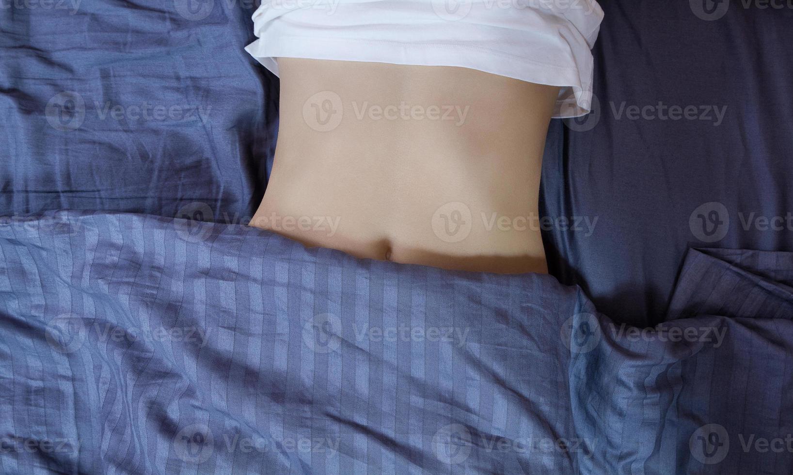 Healthy nutrition and belly health concept. Close up of woman flat stomach. Girl in bed with hungry feeling. Top view. Banner photo