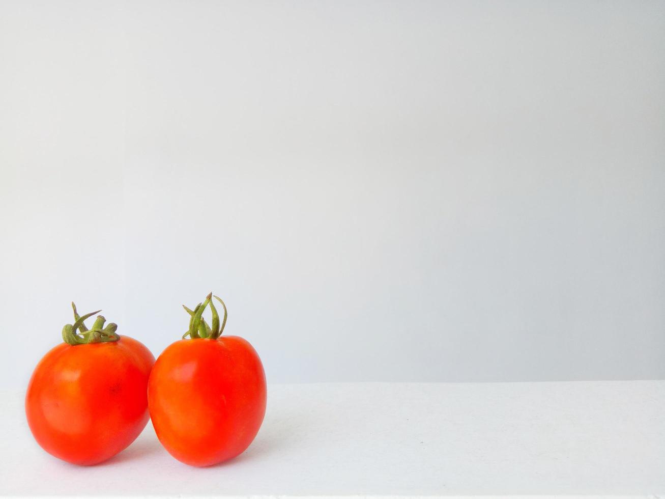 Close-up photo of two red tomatoes on a white background