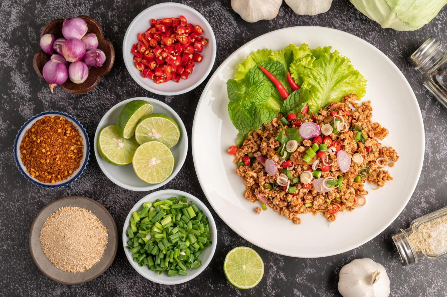 Spicy minced pork salad with chili flakes, lime, chopped green onions, chilli and roasted rice. photo
