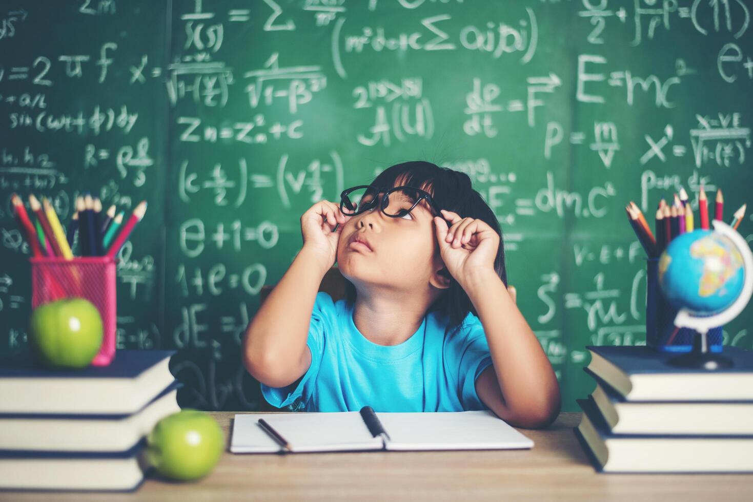 niña pensativa con libro cerca de una junta escolar foto