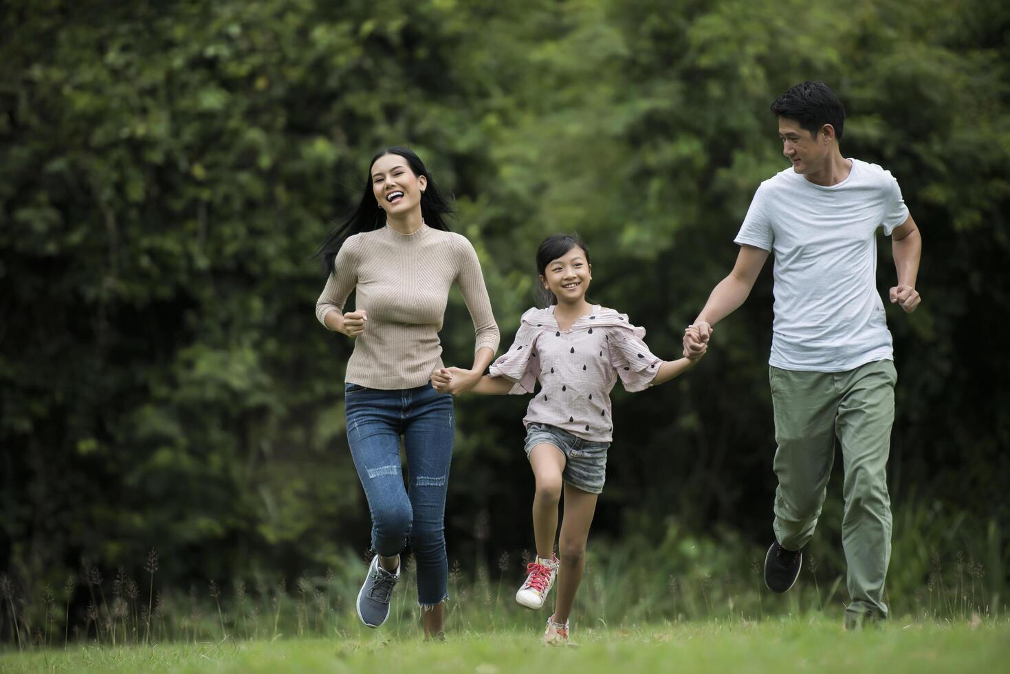 Happy family is having fun Mother, father and daughter are running in park. photo