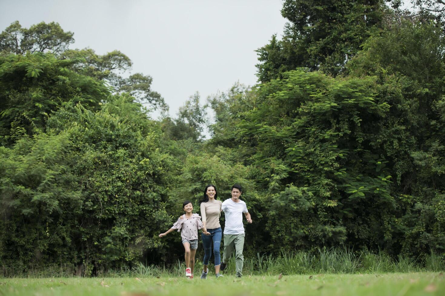 Happy family is having fun Mother, father and daughter are running in park. photo