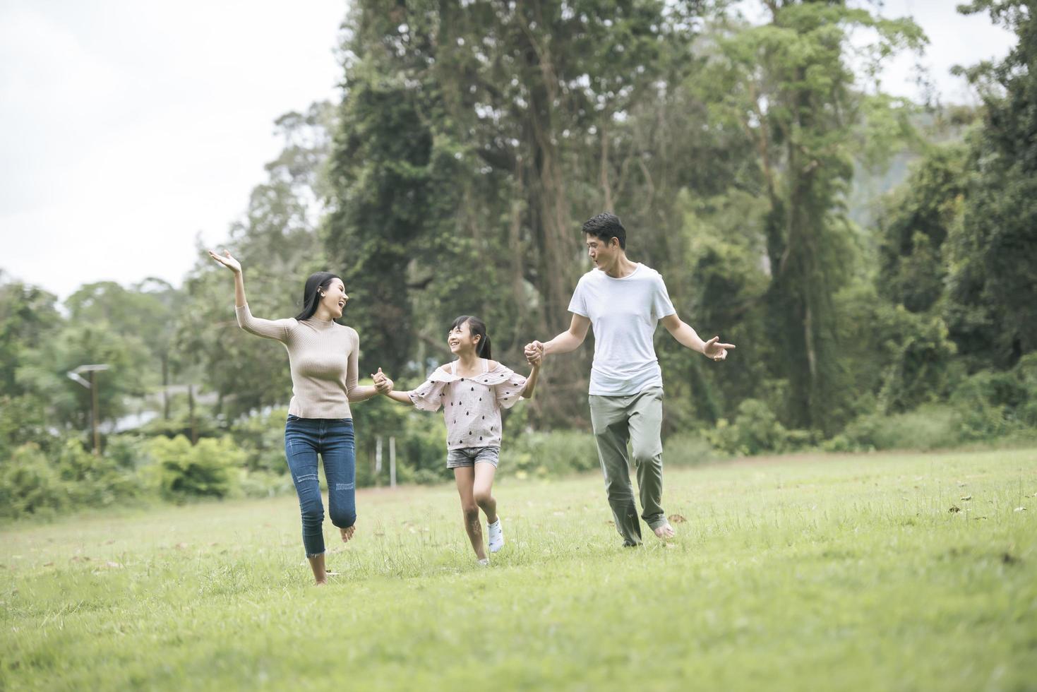 Happy family is having fun Mother, father and daughter are running in park. photo