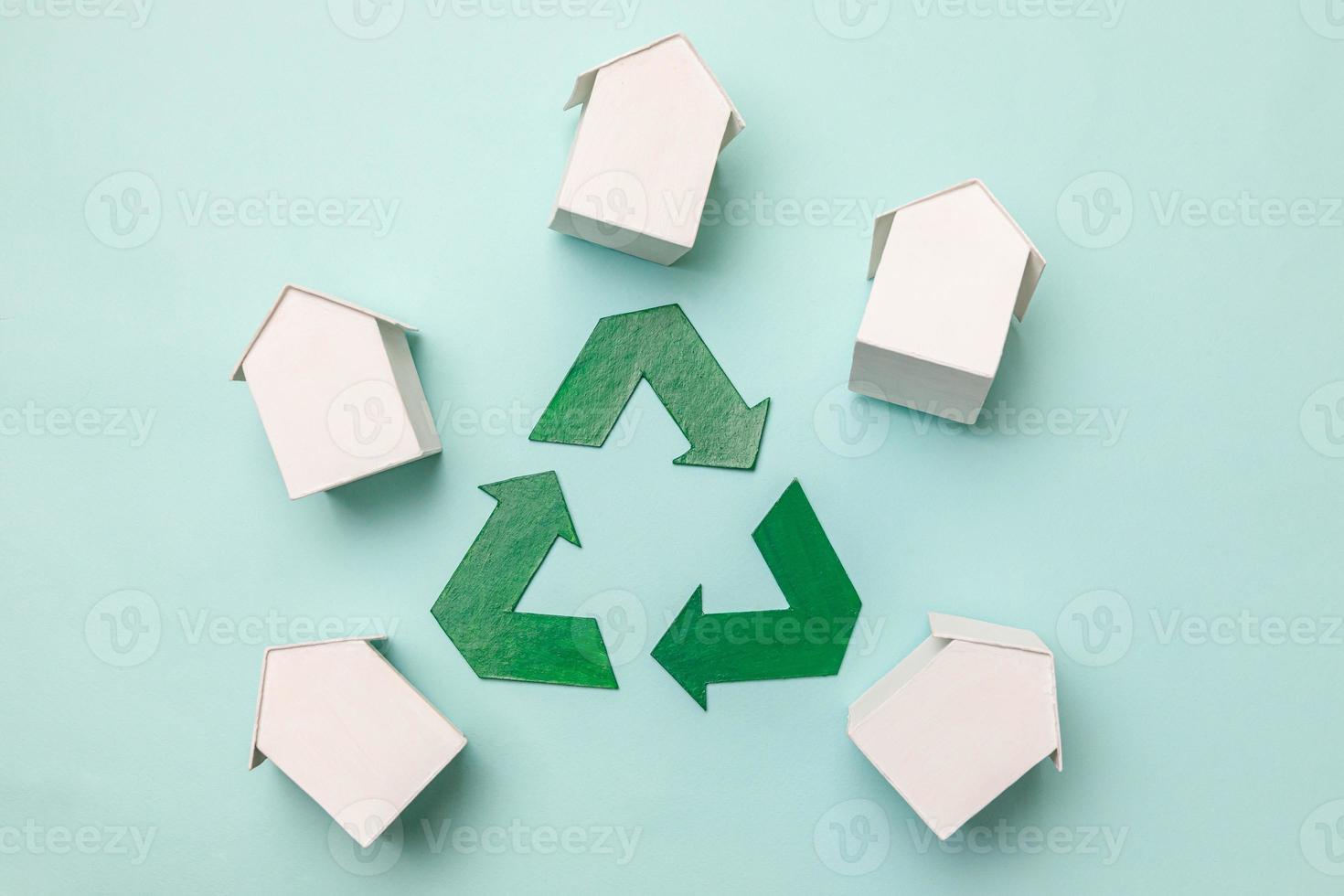 Saving energy eco friendly global warming concept. Simply design with miniature white toy model houses and recycling symbol isolated on pastel blue background. Flat lay top view copy space. photo