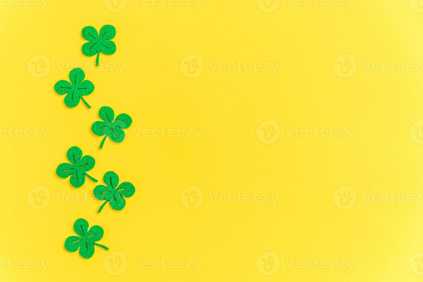 St Patricks Day background. Simply minimal design with green shamrock. Clover leaves isolated on yellow background. Symbol of Ireland. Lucky fortune wish concept. Flat lay top view layout copy space. photo