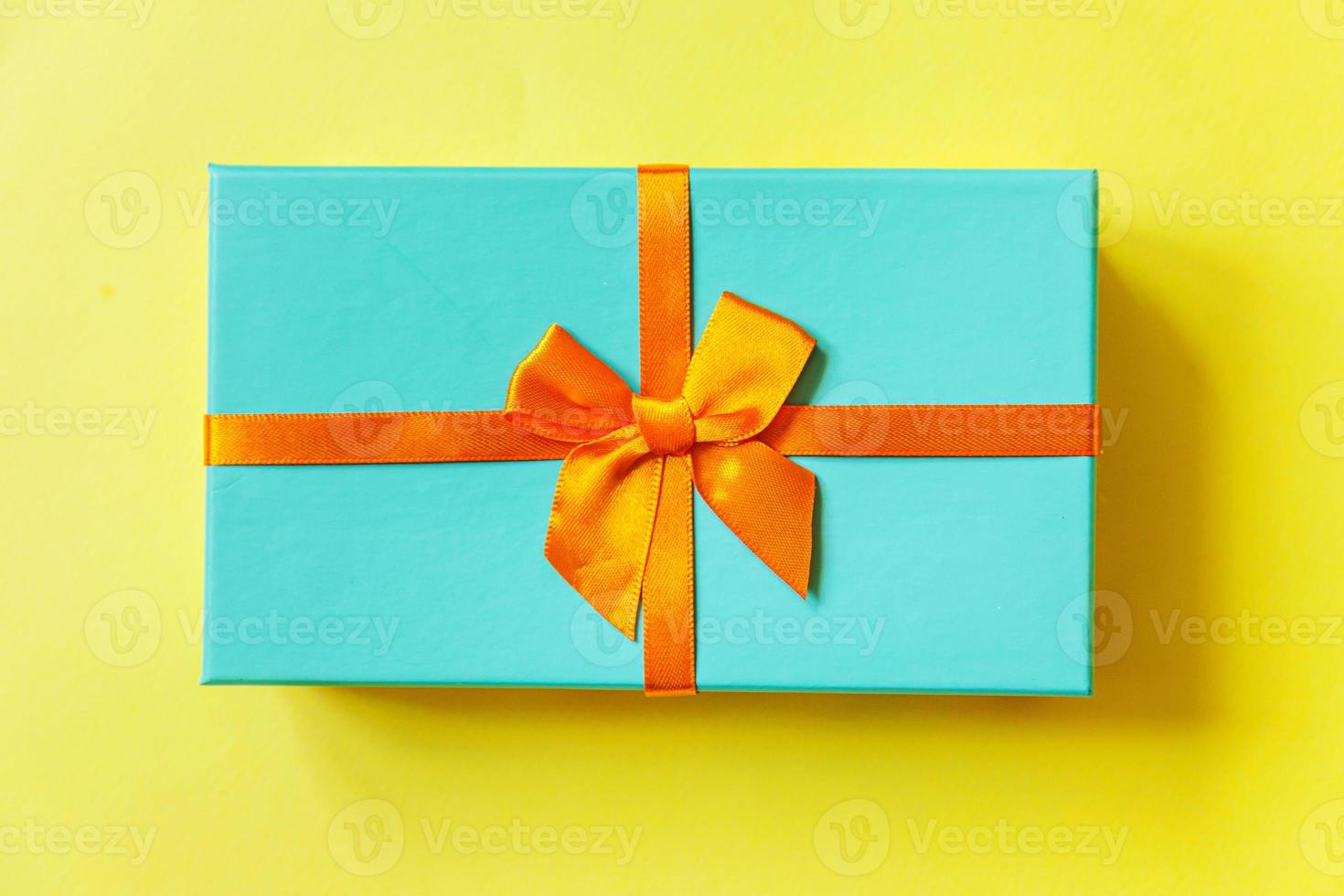 Christmas New Year birthday valentine celebration present romantic concept. Simply minimal design blue gift box isolated on yellow colorful background. Flat lay top view copy space. photo