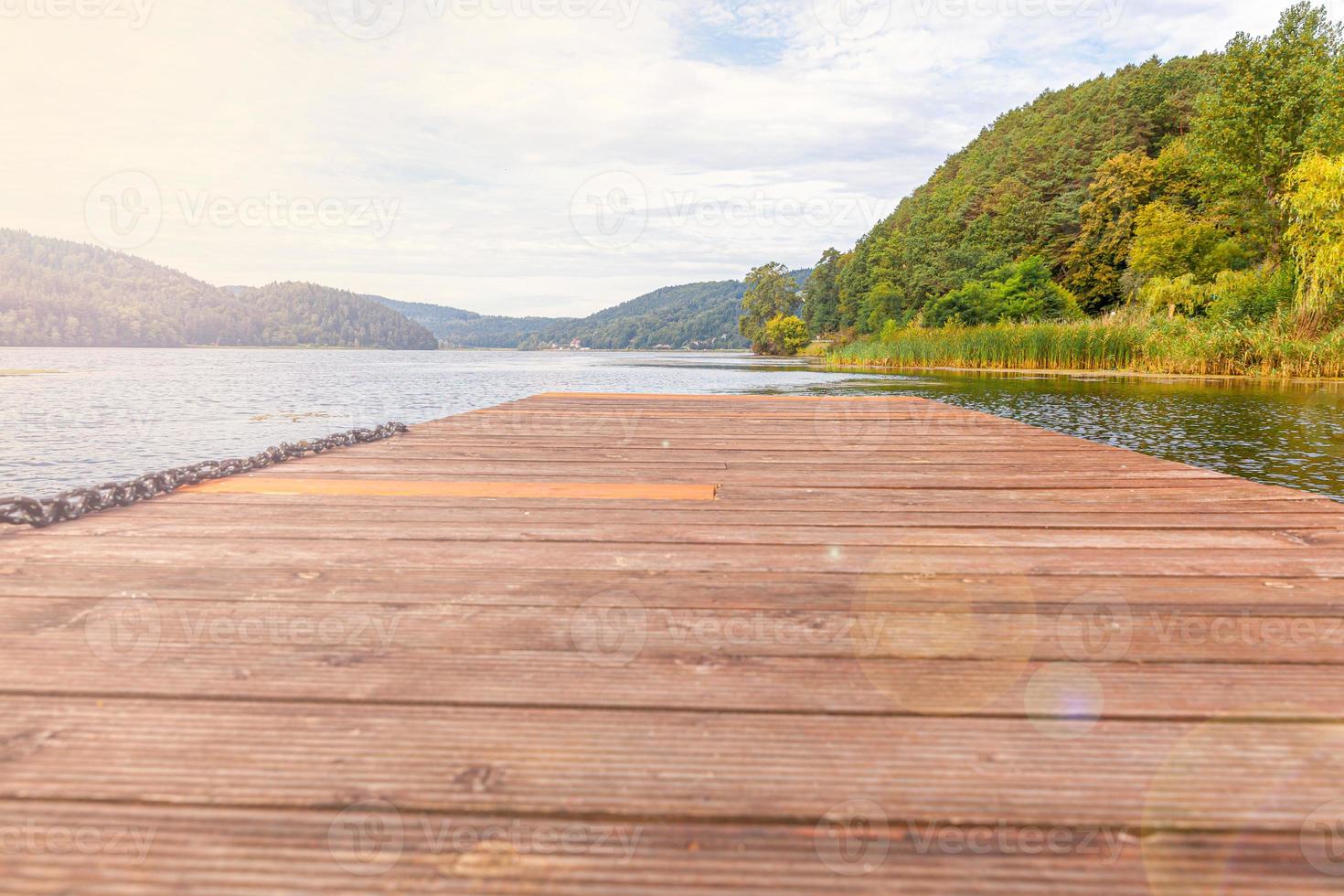 Fishing tourism relax concept. Beautiful forest lake or river on sunny summer day and old rustic wooden dock or pier. Fishing bridge on morning lake. photo