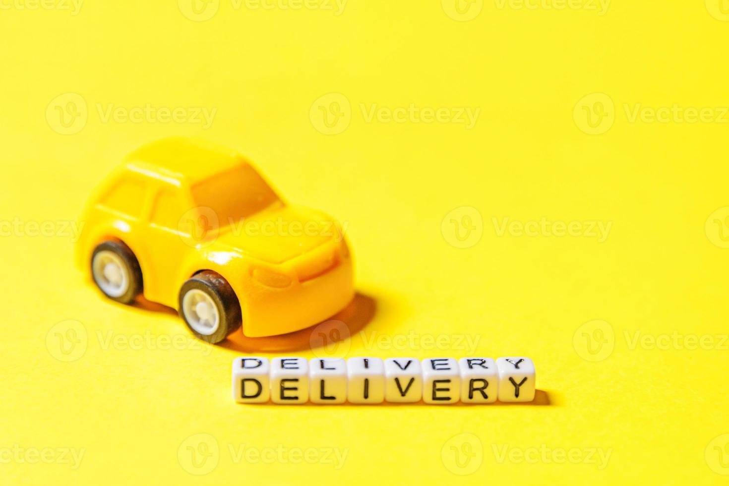 Simply design yellow toy car and inscription DELIVERY word isolated on yellow colorful background. Internet shopping online purchase e-commerce packages delivery service concept Copy space photo