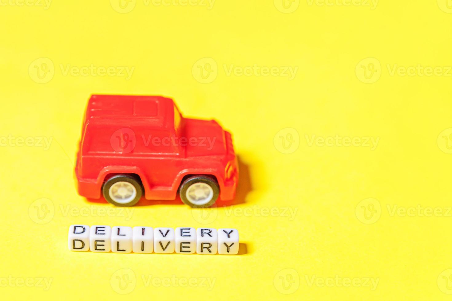 Simply design red toy car and inscription DELIVERY word isolated on yellow colorful background. Internet shopping online purchase e-commerce packages delivery service concept Copy space photo