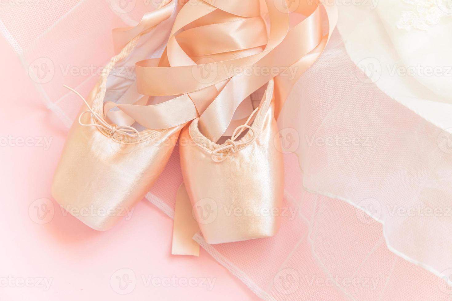 nuevos zapatos de ballet beige pastel con cinta satinada y falda tutut aislados en fondo rosa. Bailarina de punta clásica para entrenamiento de baile. concepto de escuela de ballet. vista superior plana, espacio de copia foto