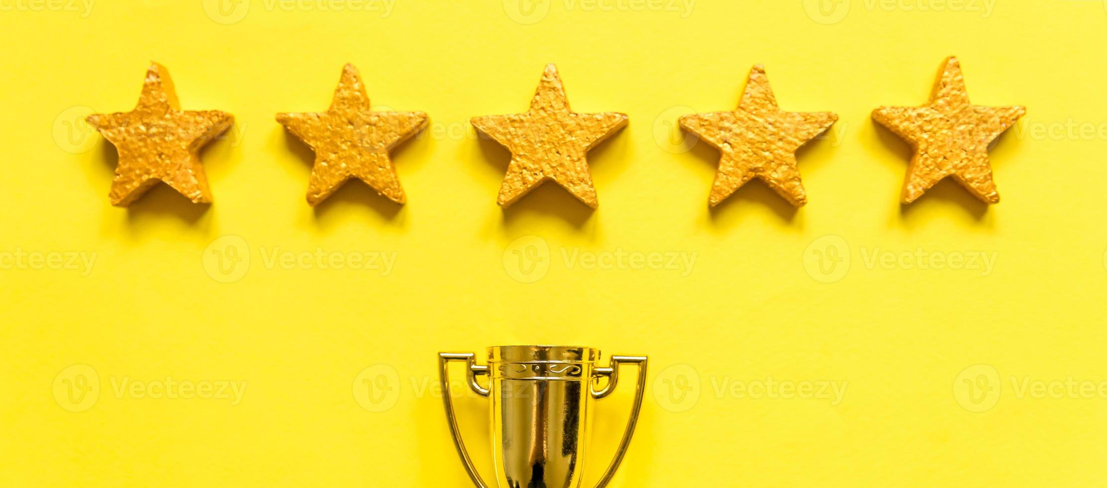 Simply flat lay design winner or champion gold trophy cup and 5 stars rating isolated on yellow background. Victory first place of competition. Winning or success concept. Top view copy space. banner photo