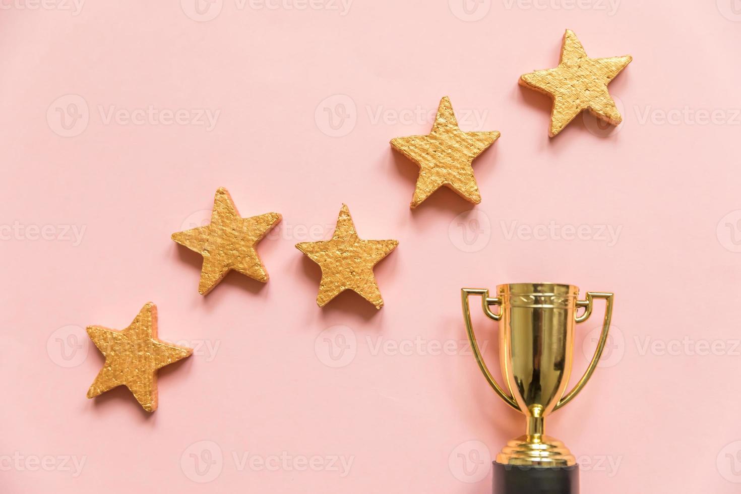 Simply flat lay design winner or champion gold trophy cup and 5 stars rating isolated on pink pastel background. Victory first place of competition. Winning or success concept. Top view, copy space photo