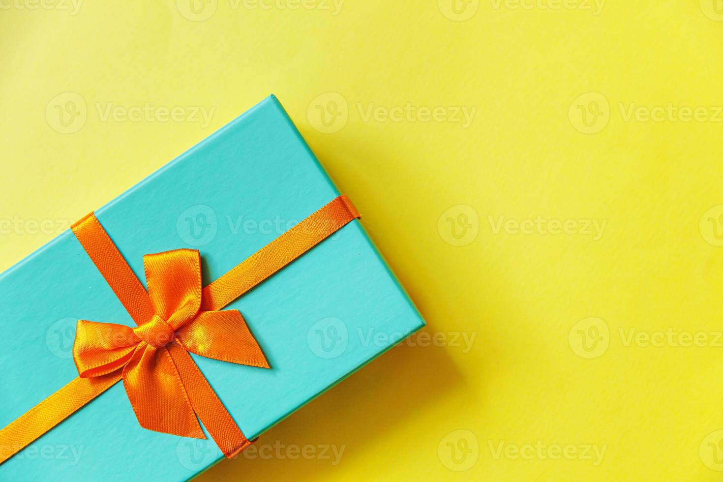 Christmas New Year birthday valentine celebration present romantic concept. Simply minimal design blue gift box isolated on yellow colorful background. Flat lay top view copy space. photo