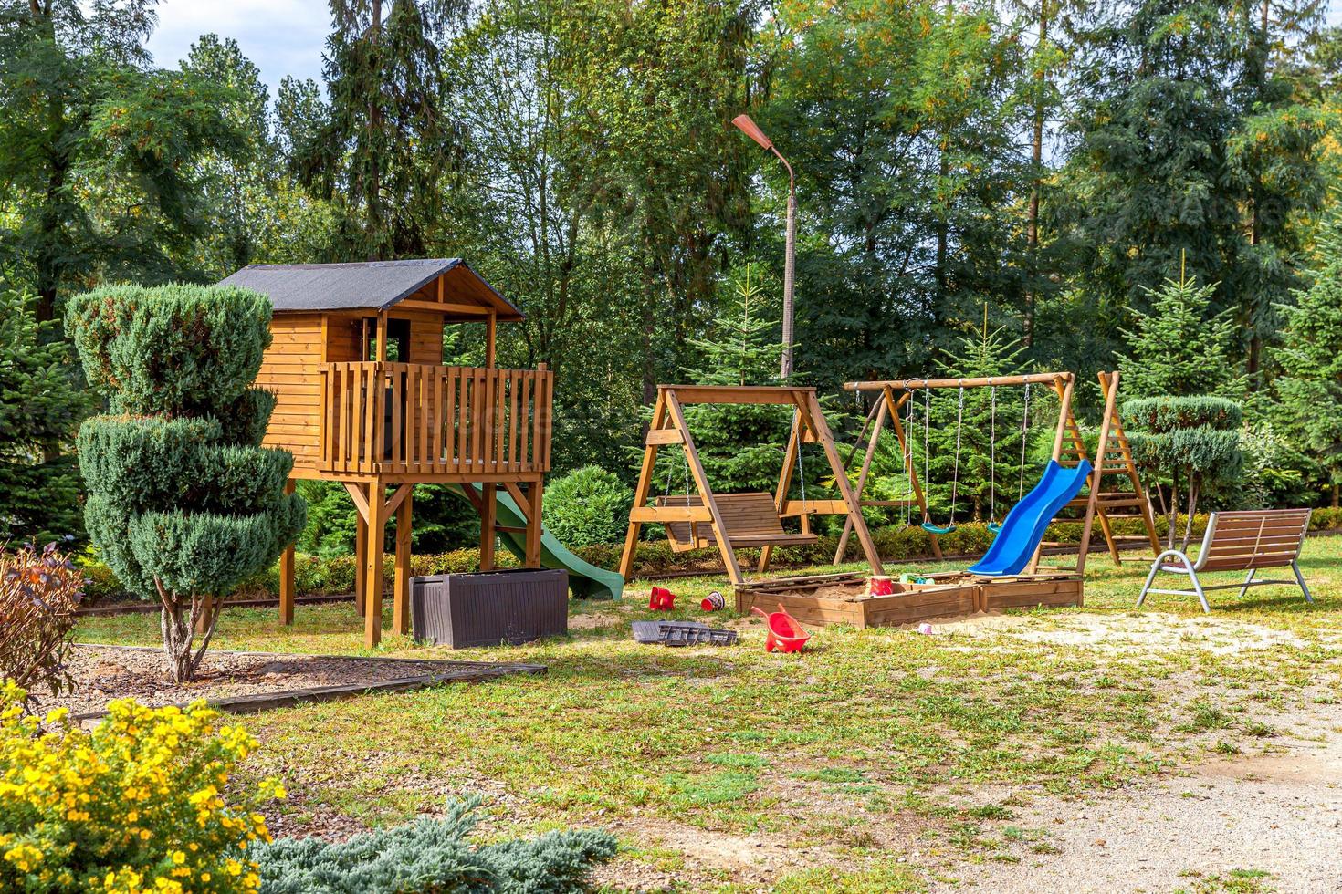 Empty modern wooden children playground set on green yard in public park in summer day. Funny toy land for kids. Urban exercise activities for child outdoors. Neighborhood childhood concept. photo