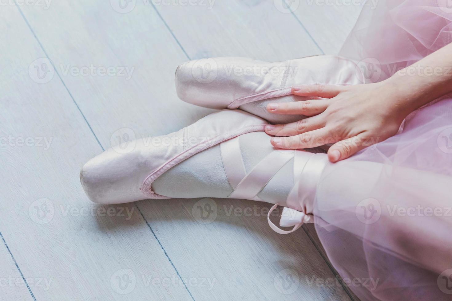 Ballerina hands puts pointe shoes on leg in dance class photo