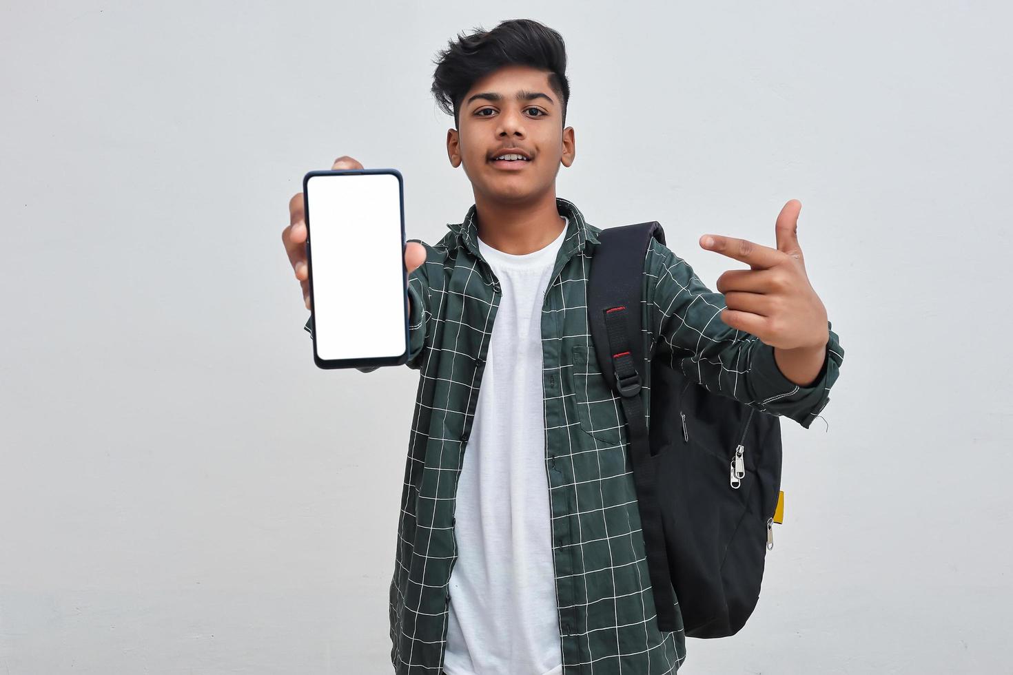 Young indian collage boy showing smartphone screen on white background. photo