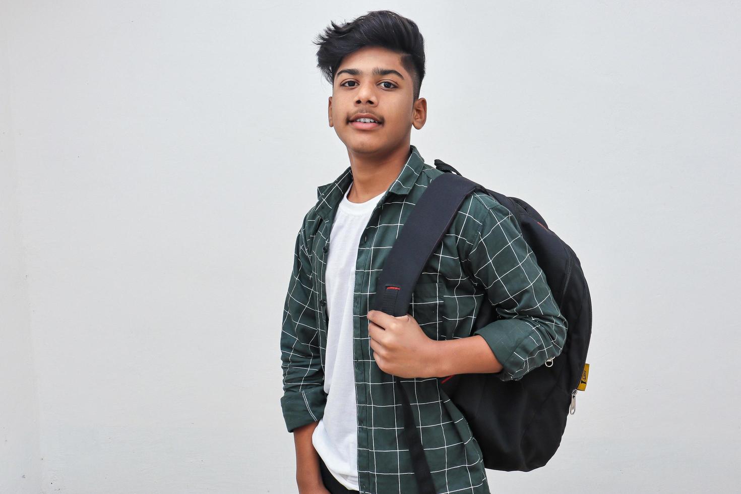 Handsome Indian collage boy standing on white background. photo