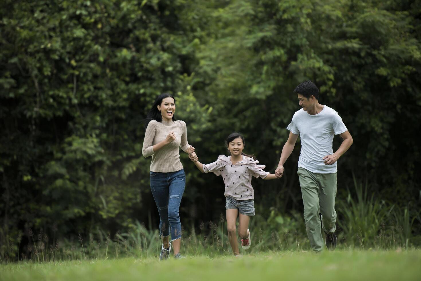 Happy family is having fun Mother, father and daughter are running in park. photo