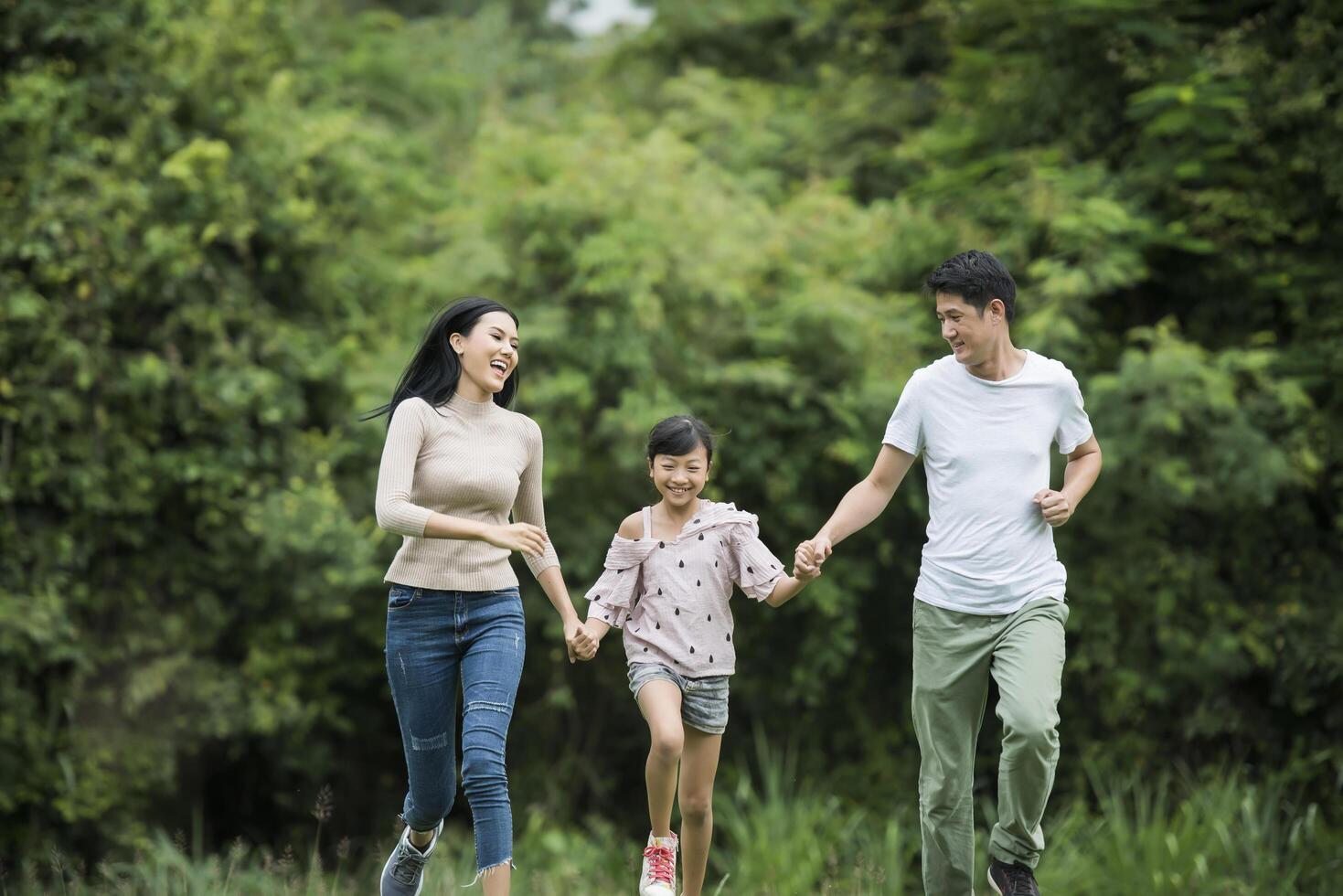 Happy family is having fun Mother, father and daughter are running in park. photo