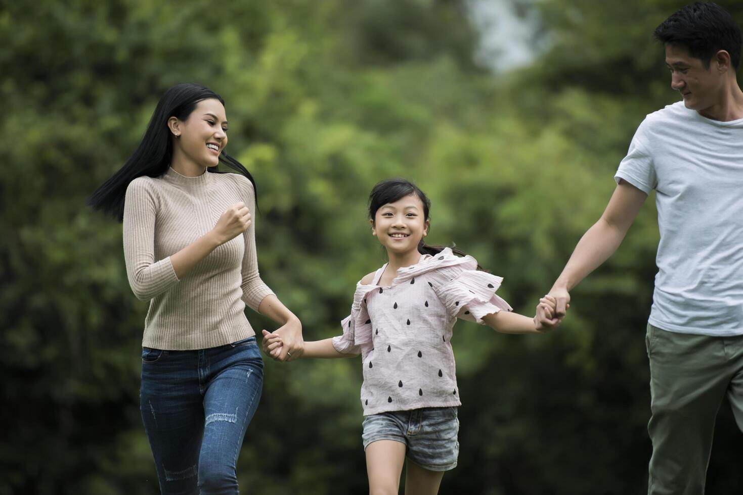 Happy family is having fun Mother, father and daughter are running in park. photo