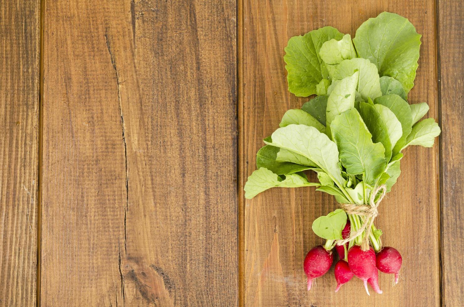 Bunch of fresh radish on brown wooden table. photo
