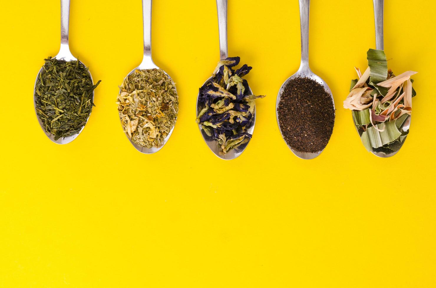 Leaves of different varieties of tea in spoons photo