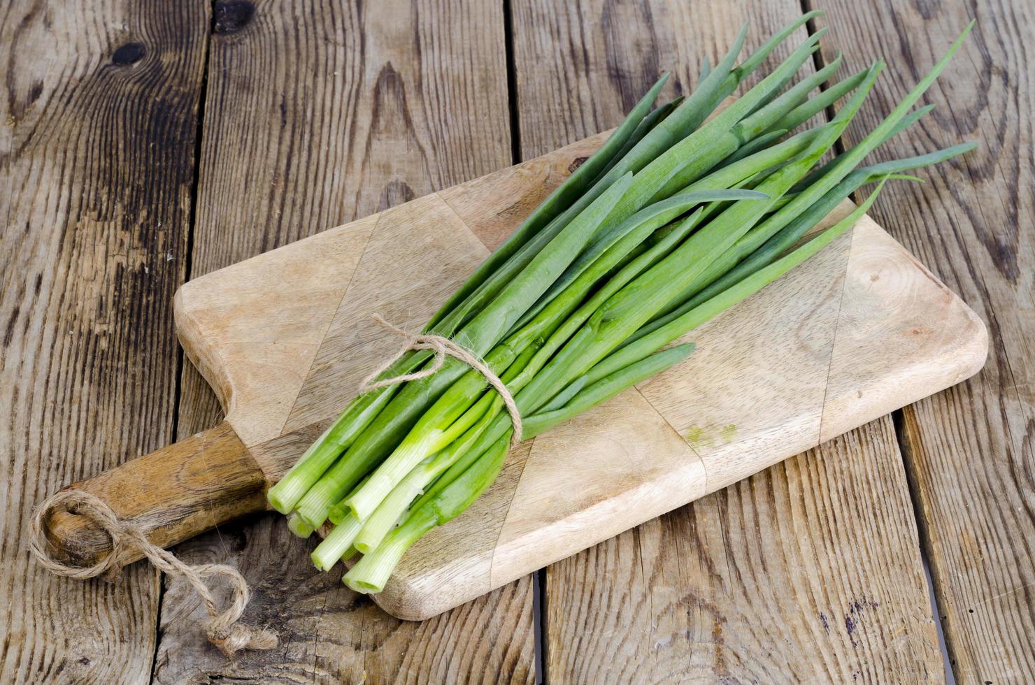 Bunch of fresh green onions on wooden table. photo