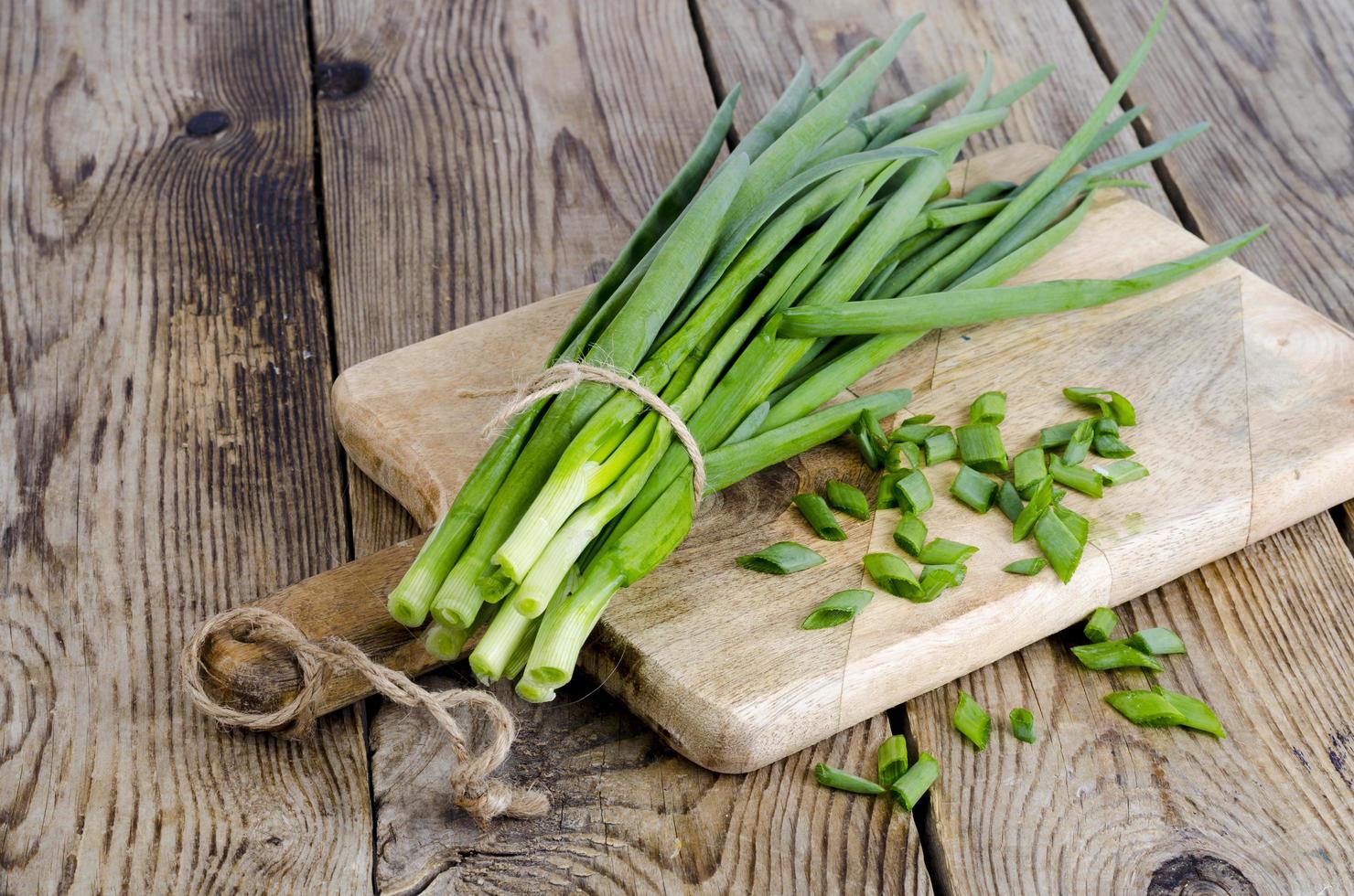 Bunch of fresh green onions on wooden table. photo