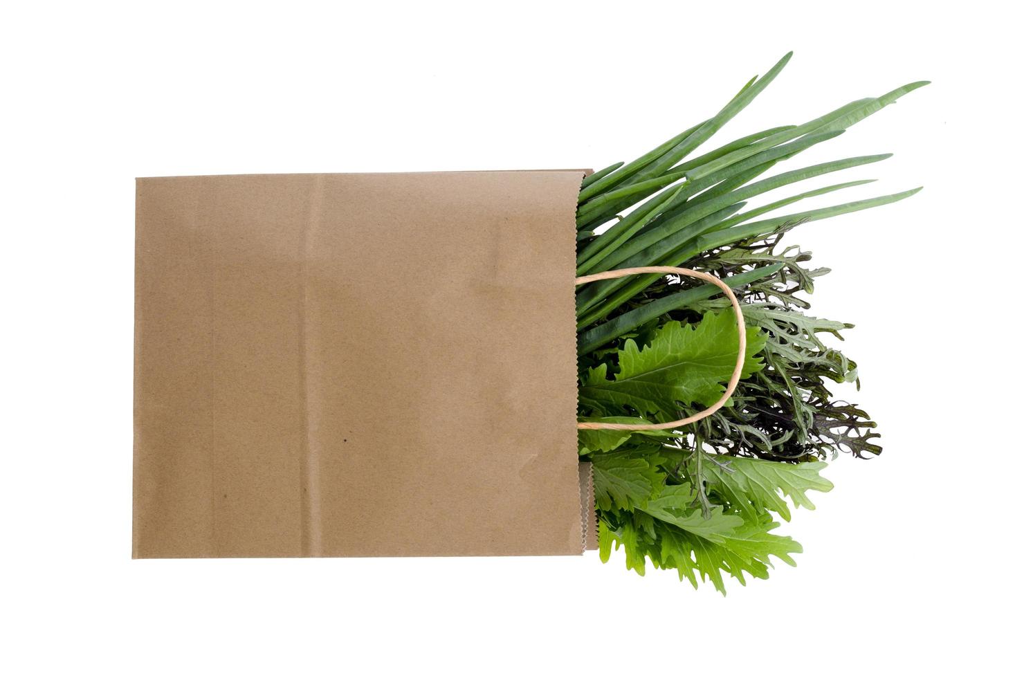 Fresh greens in paper bag on white photo