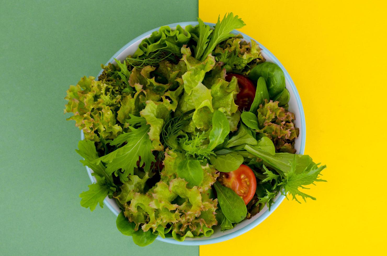 Bowl of mixed salad on bright, color background. photo