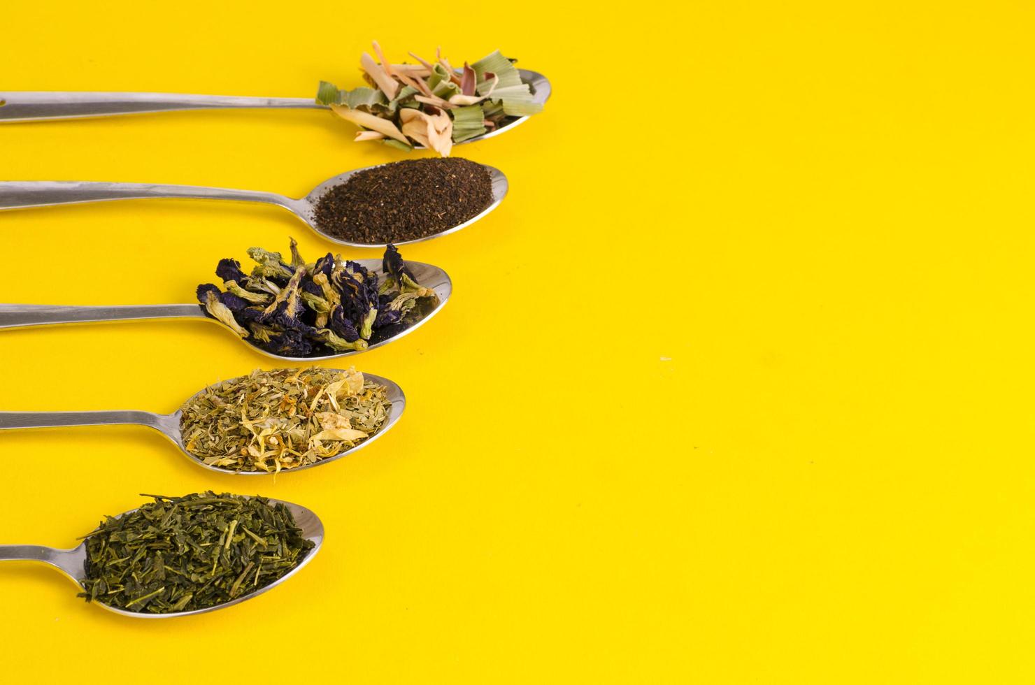 Leaves of different varieties of tea in spoons photo