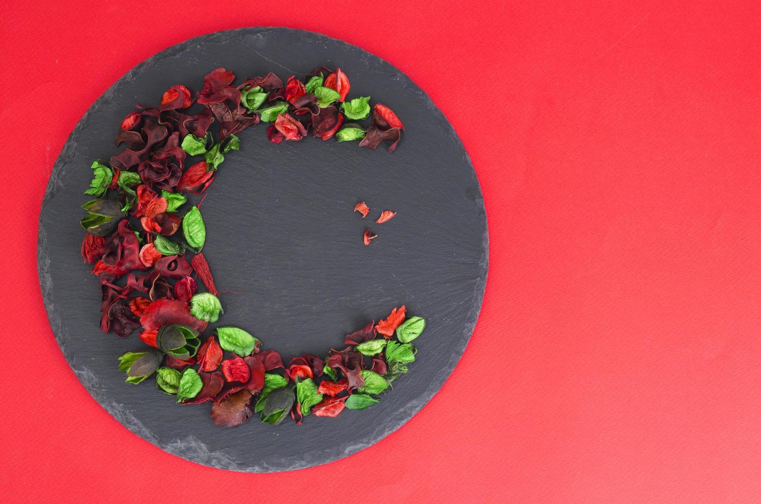 Creative flower composition in form of crescent of dry flowers and petals, green leaves. Top view, flat lay. photo