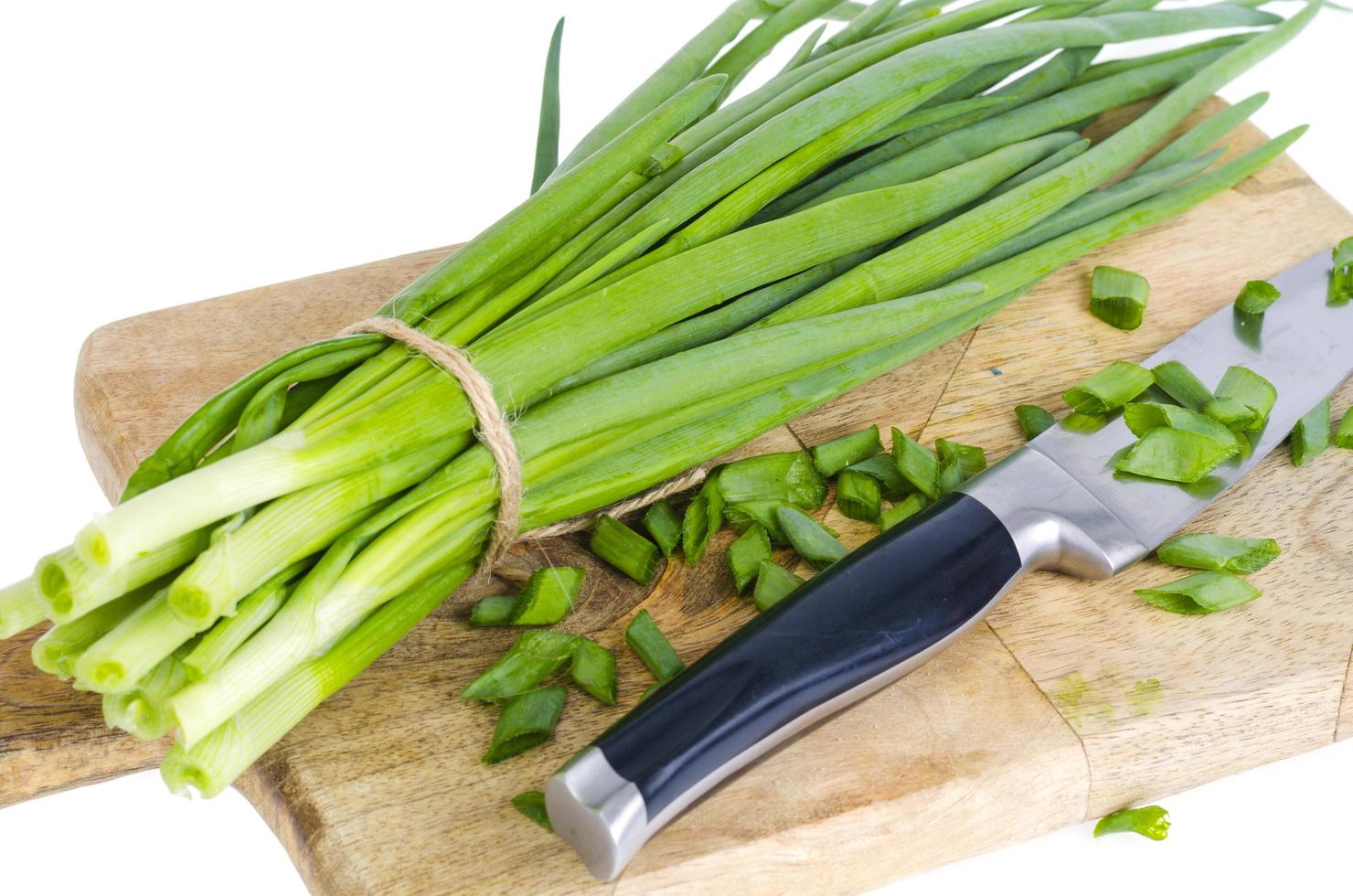Use of fresh green onions in cooking, kitchen wooden board. photo