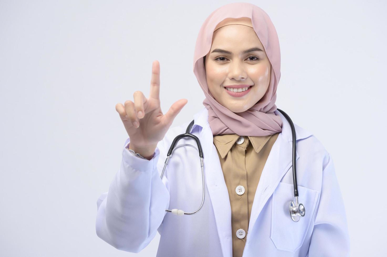 Female muslim doctor with hijab over white background studio. photo