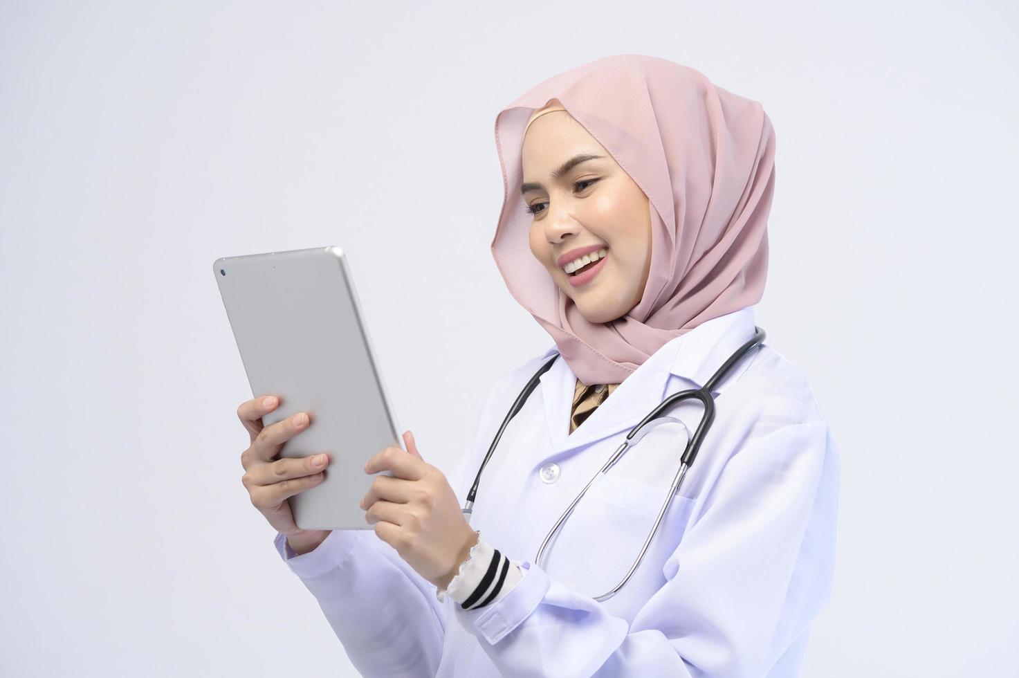 Female muslim doctor with hijab over white background studio. photo