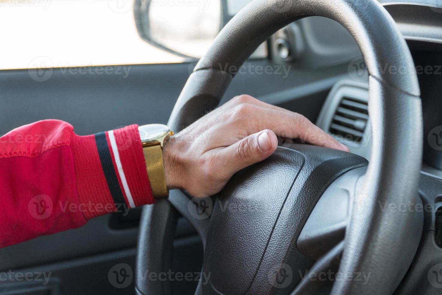 men's hand with a watch on the steering wheel of a modern car photo