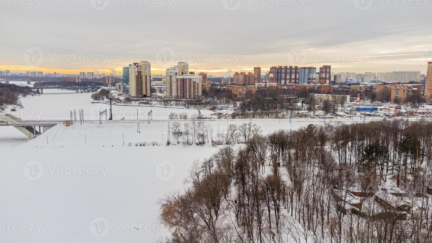 There is a view from a height using a quadcopter along the icy river and high-rise buildings photo