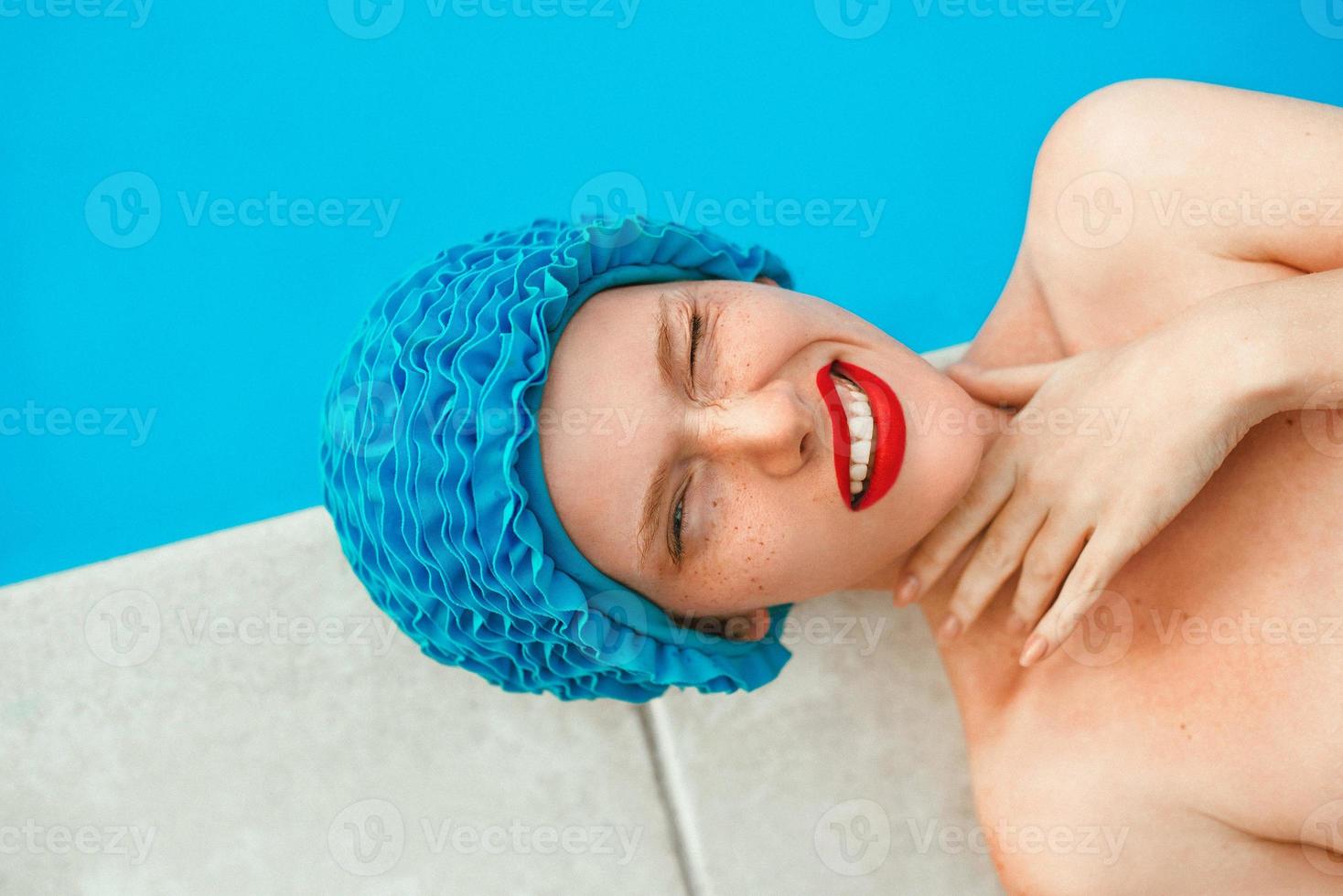 portrait of smiling beautiful woman in pool cap laying by the swimming pool. Summer, wellness, recreation, travel, happiness concept photo