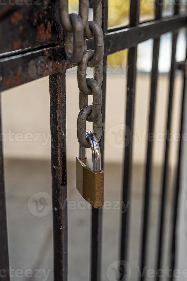 Hanging chain from a metal door with locked padlock at the end. photo