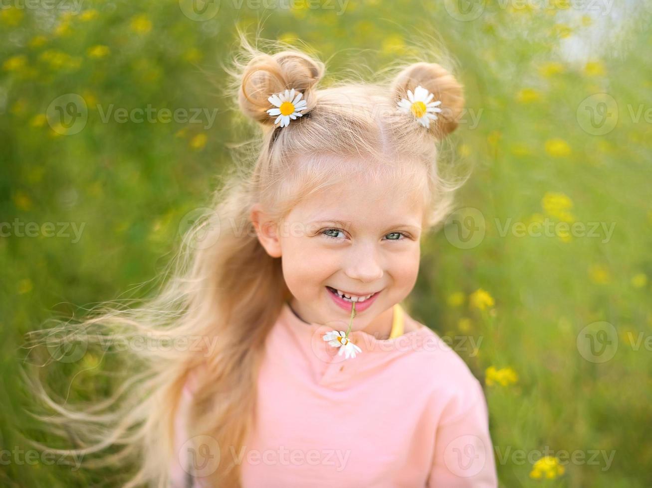 linda niña rubia sonriente con manzanilla en su peinado y en sus dientes foto