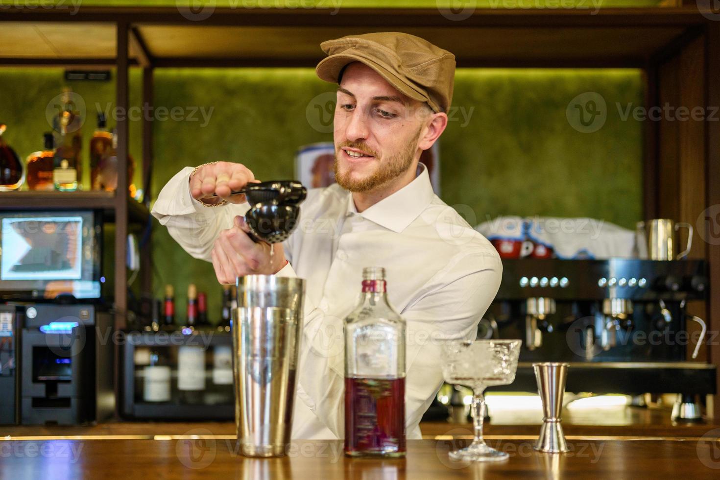 barman masculino exprimiendo limón en un cóctel en un pub foto