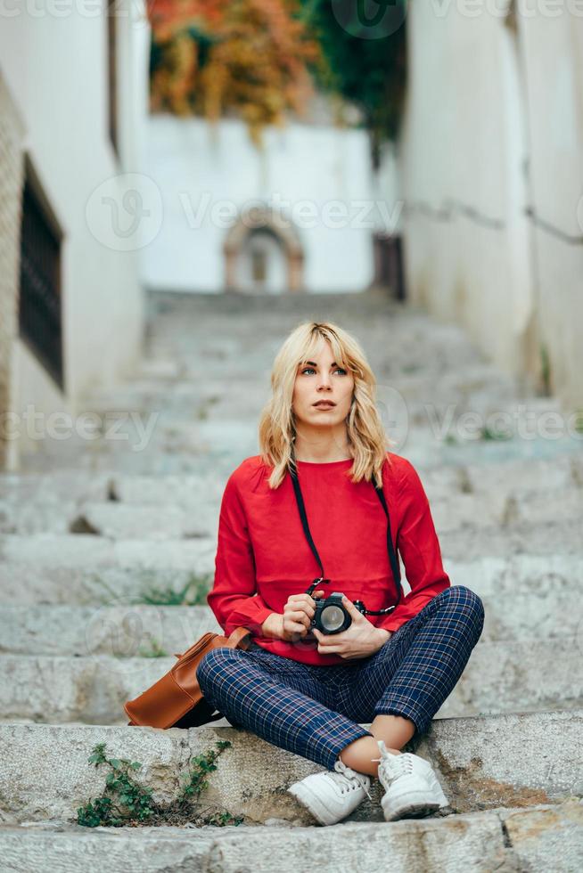 Young woman taking photographs with an old camera in a beautiful city. photo