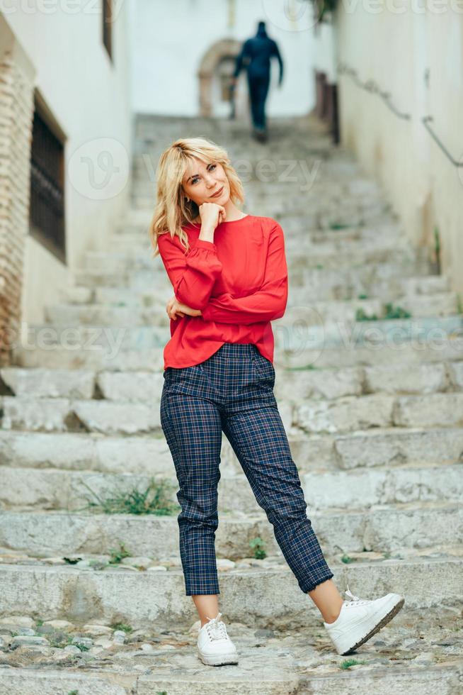 Happy young blond woman standing on beautiful steps in the street. photo