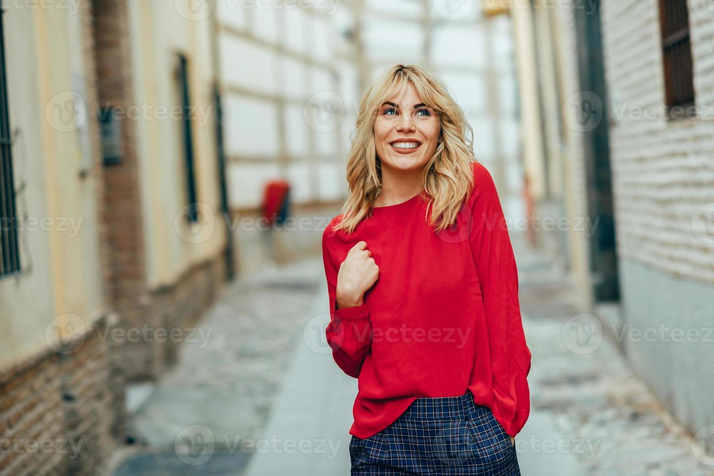 Happy young blond woman walking down the street. photo