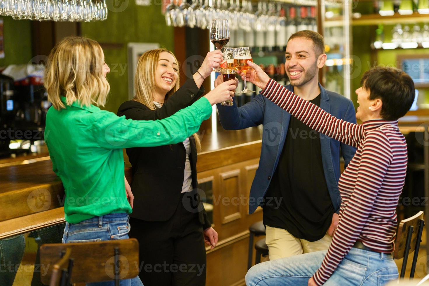 amigos optimistas proponiendo tostadas en un pub foto