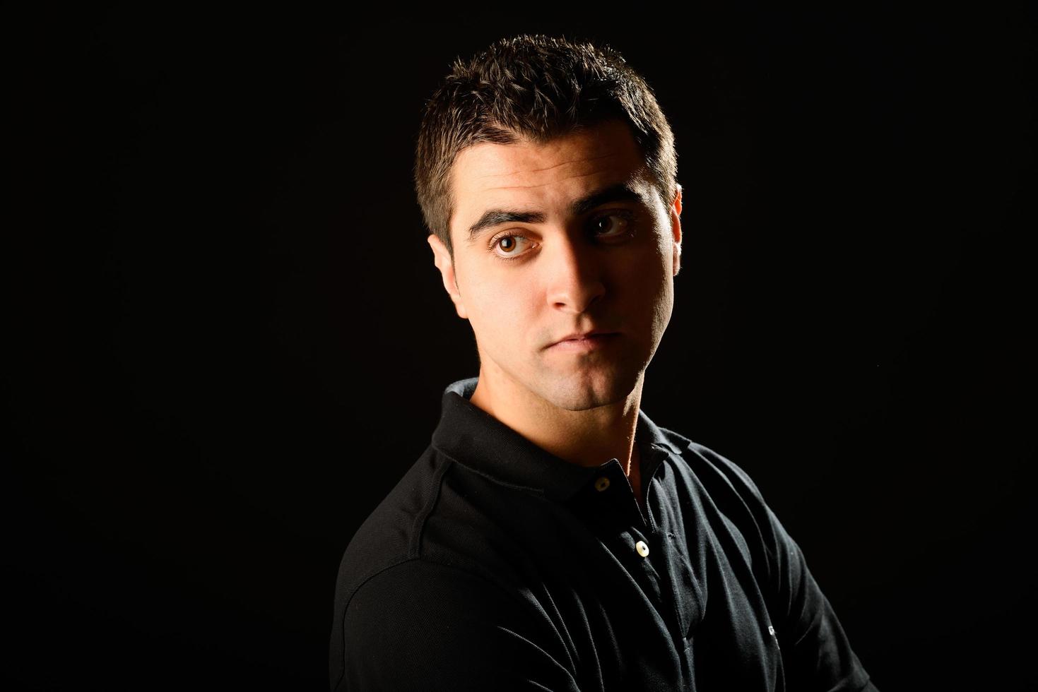 Young casual man on black background photo