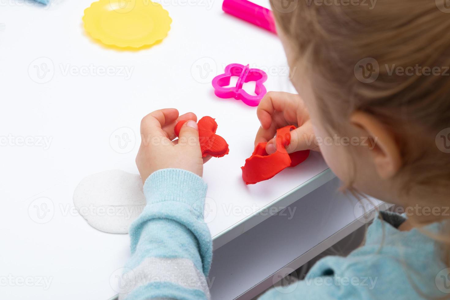 la chica de la mesa está jugando con plastilina. juegos infantiles para la motricidad fina foto