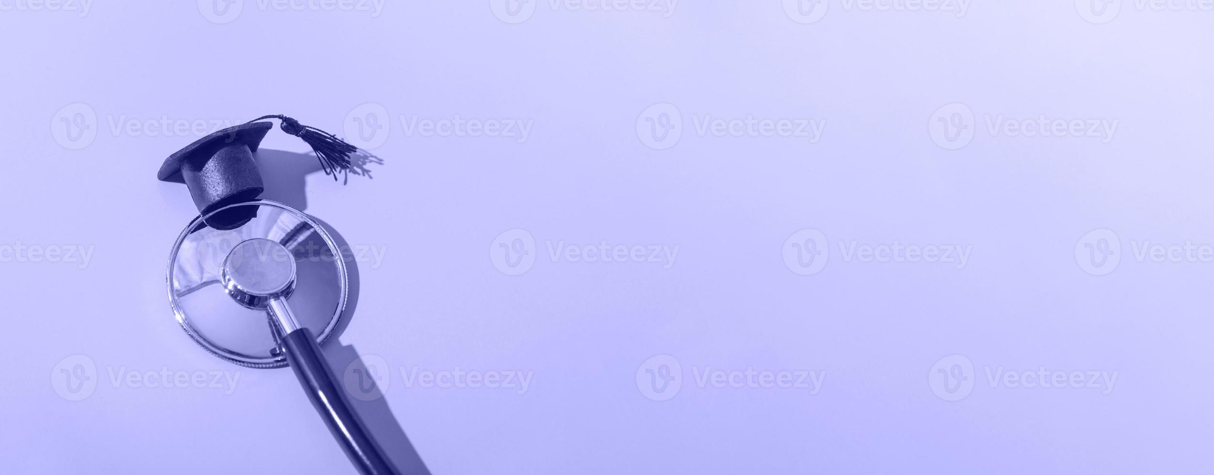 Stethoscope and graduation cap with hard shadow on blue background. Medical education concept, closeup with copy space photo