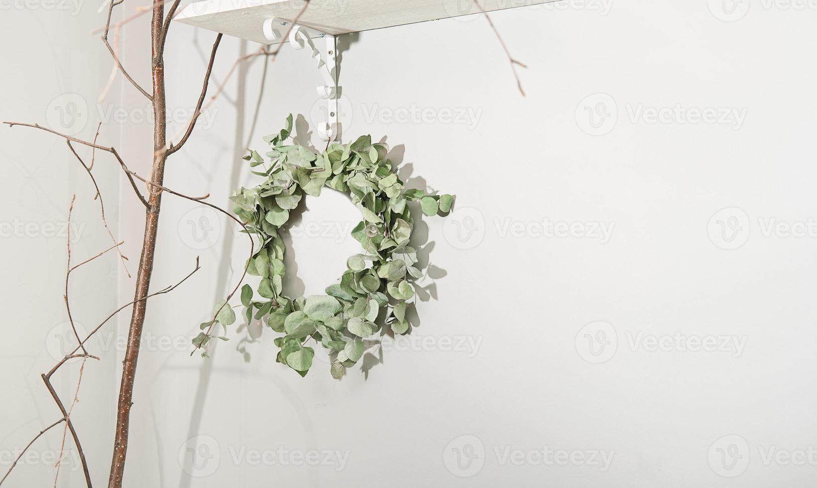 eucaliptus branch wreath hanging on a wall, spring decor in a rustic style home. seasonal decoration for spring holidays. copy space. photo